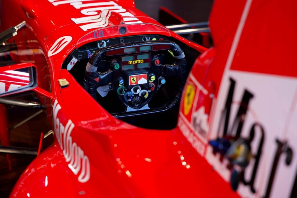 Vibrant red Formula 1 car cockpit, showcasing steering wheel and intricate details.