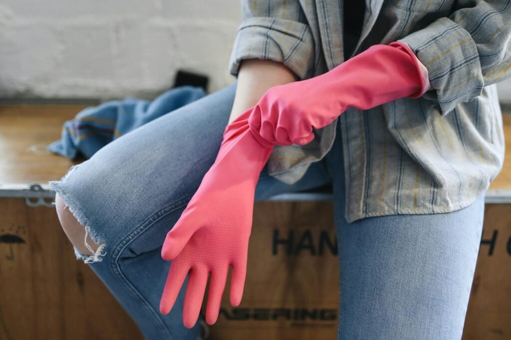 A person wears pink rubber gloves indoors, preparing for cleaning tasks.