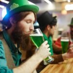 Men celebrating St. Patrick's Day with green beer at a pub, showcasing a festive gathering.