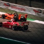 a couple of racing cars driving down a race track
